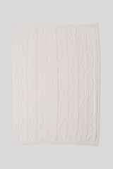 Cream knitted blanket with a geometric pattern on a light gray background