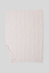 Cream cable knit blanket on a light gray background