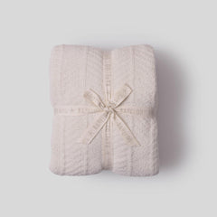 Folded textured blanket with a bow on a light gray background
