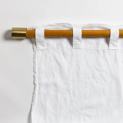 White curtain from Bella Notte Linens with a wooden rod on a light gray background