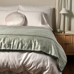 Paloma Bed End Blanket from Bella Notte Linens in the color Eucalpytus displayed on a bed with shams and a duvet also from Bella Notte Linens. 
