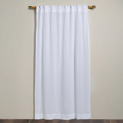 White Linen curtain from Bella Notte Linens hanging on a wooden rod against a beige wall.